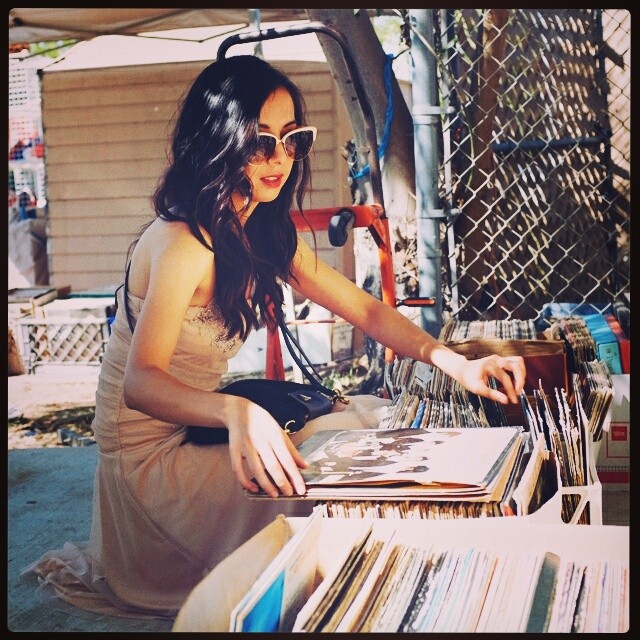 A pretty girl checking out some vinyl at a garage sale down the street from the wedding she just attended.